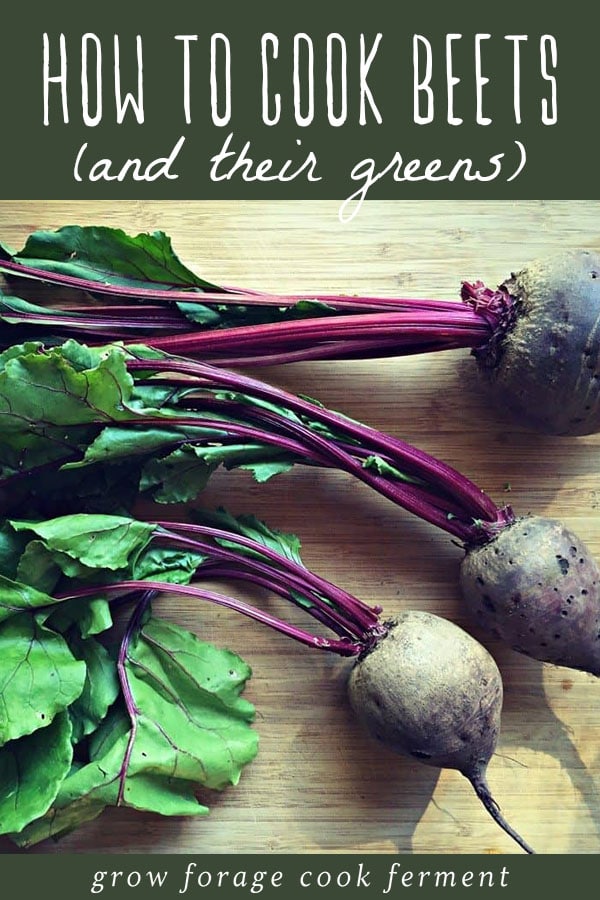 Fresh beets and beet greens on a cutting board.