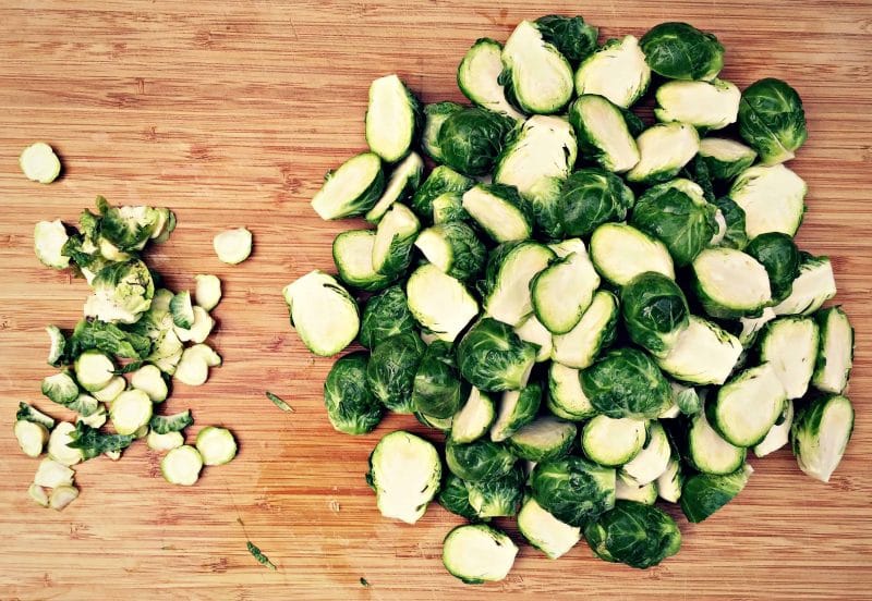 cut brussels sprouts on a bamboo cutting board