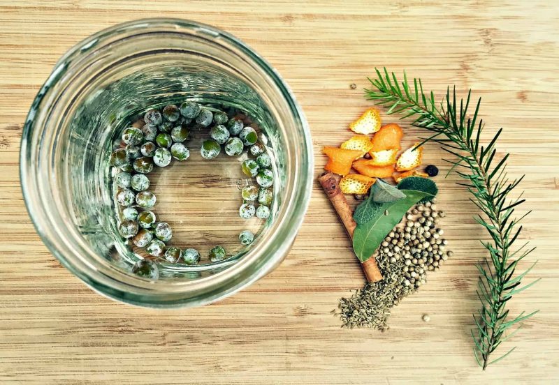 juniper berries in vodka and herbs on a table