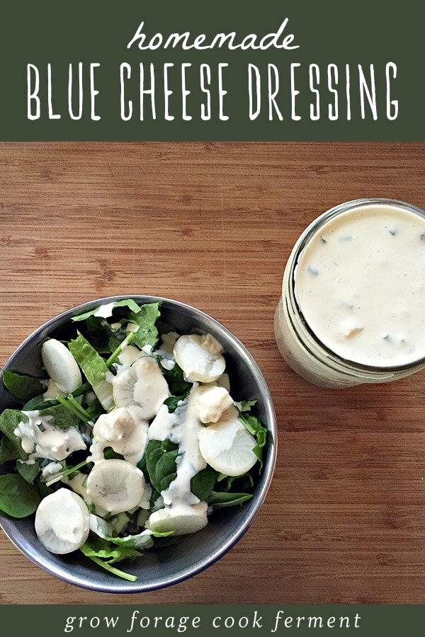 A bowl of salad dressed with homemade blue cheese dressing, and a mason jar of homemade blue cheese dressing.