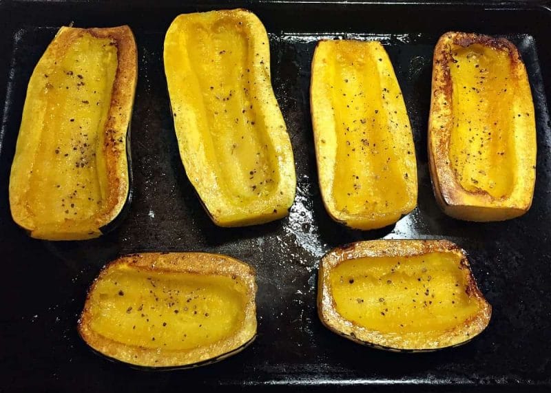 roasted delicata squash halves on a baking sheet