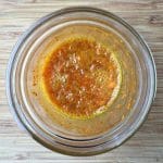 Bubbling fermented turmeric bug in a glass jar on a wood surface.