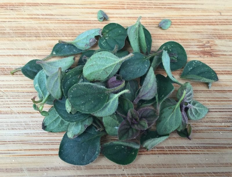 fresh oregano leaves on a cutting board