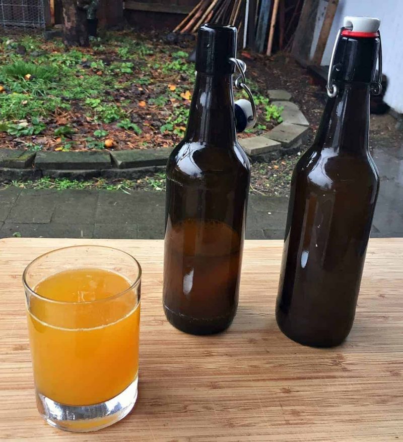 a glass of fermented turmeric soda and two flip top bottles