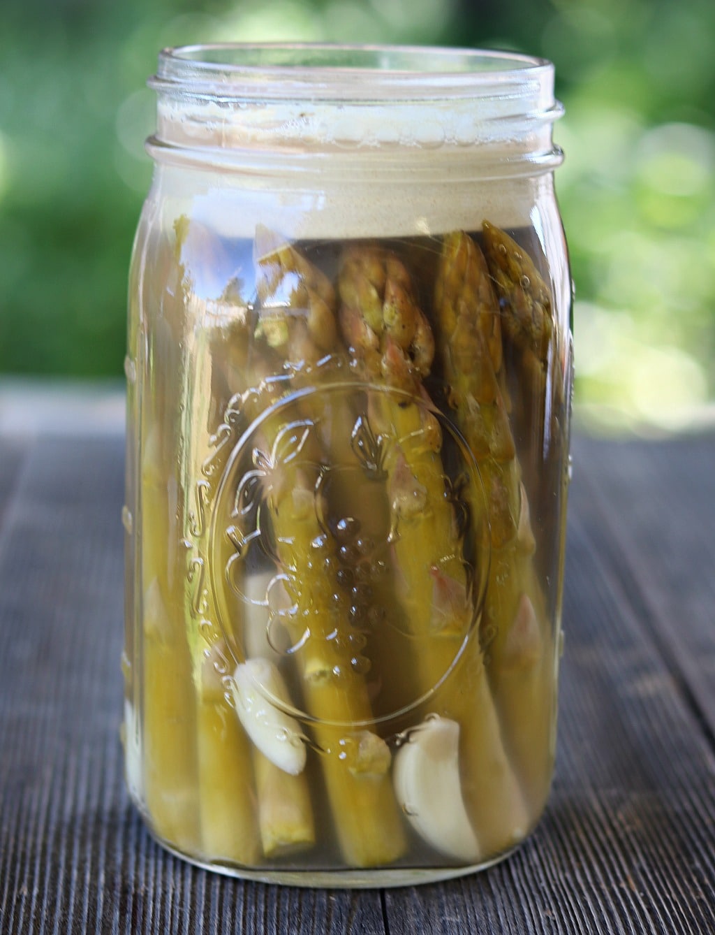 fermented asparagus in a jar with a weight