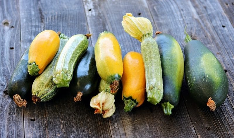 a pile of different colored zucchini on a wooden board