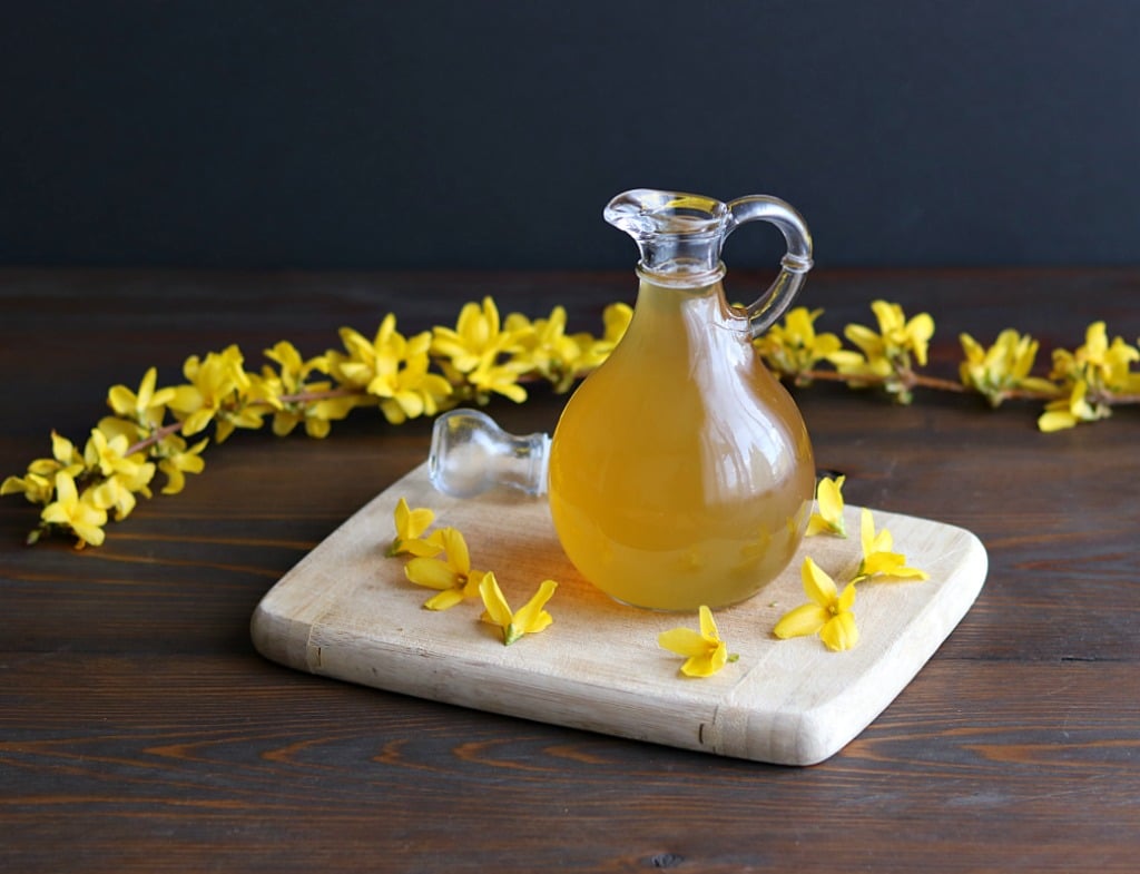 a small jug of forsythia syrup on a cutting board
