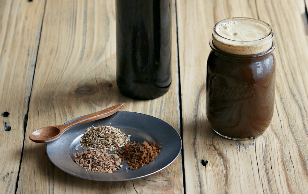 a glass of fermented root beer and a plate with dried roots and herbs