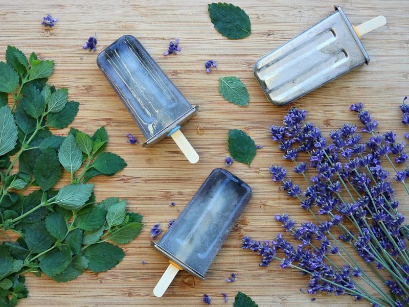 herbal popsicles on a board with fresh lavender and lemon balm