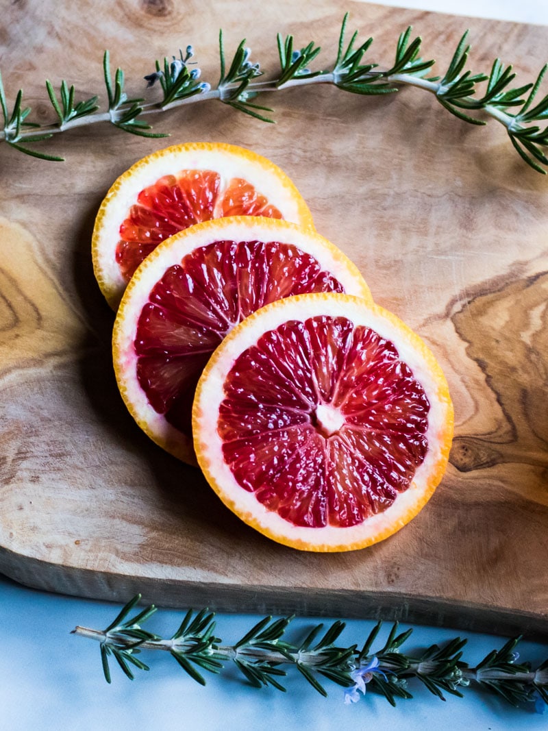 blood orange slices and rosemary on a wooden cutting board