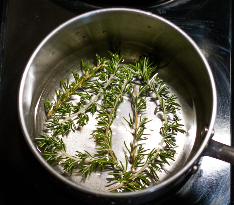 a pot with water and fresh rosemary sprigs
