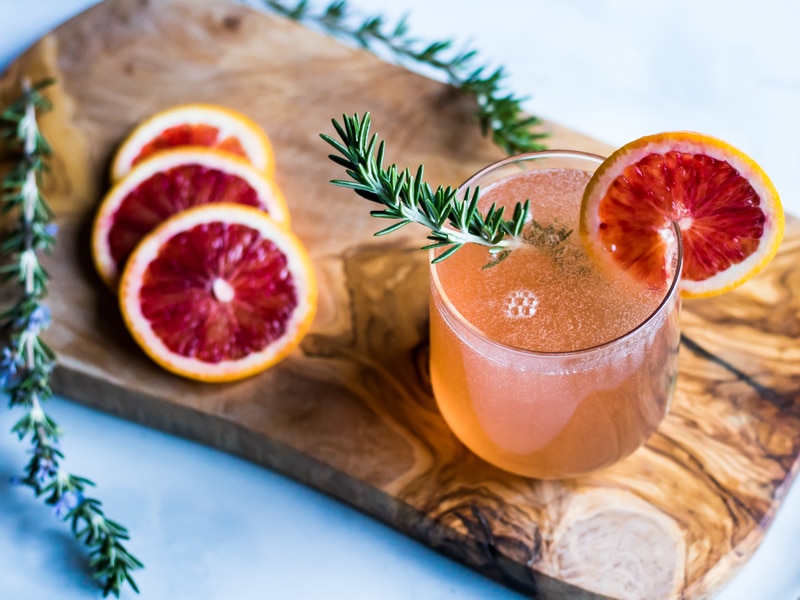 a glass of rosemary champagne cocktail with orange