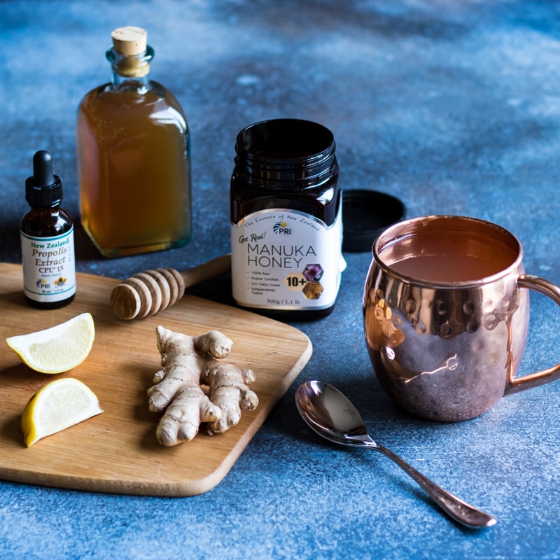 a cup of honey vinegar elixir with a jar of manuka honey