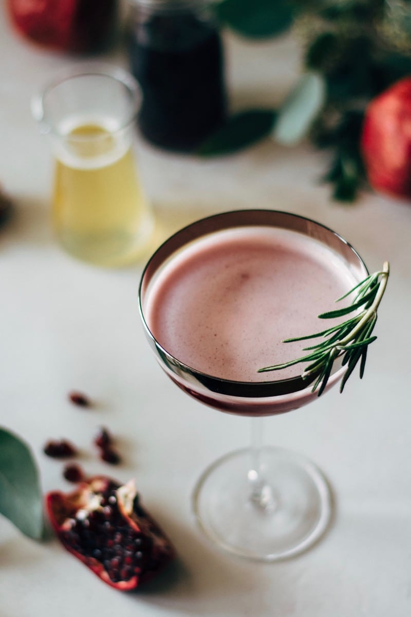 pomegranate martini with a rosemary sprig garnish