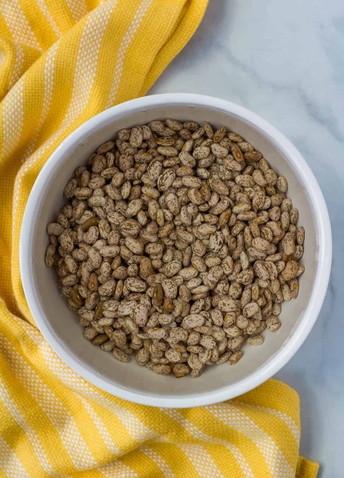 pinto beans soaking in a bowl of water