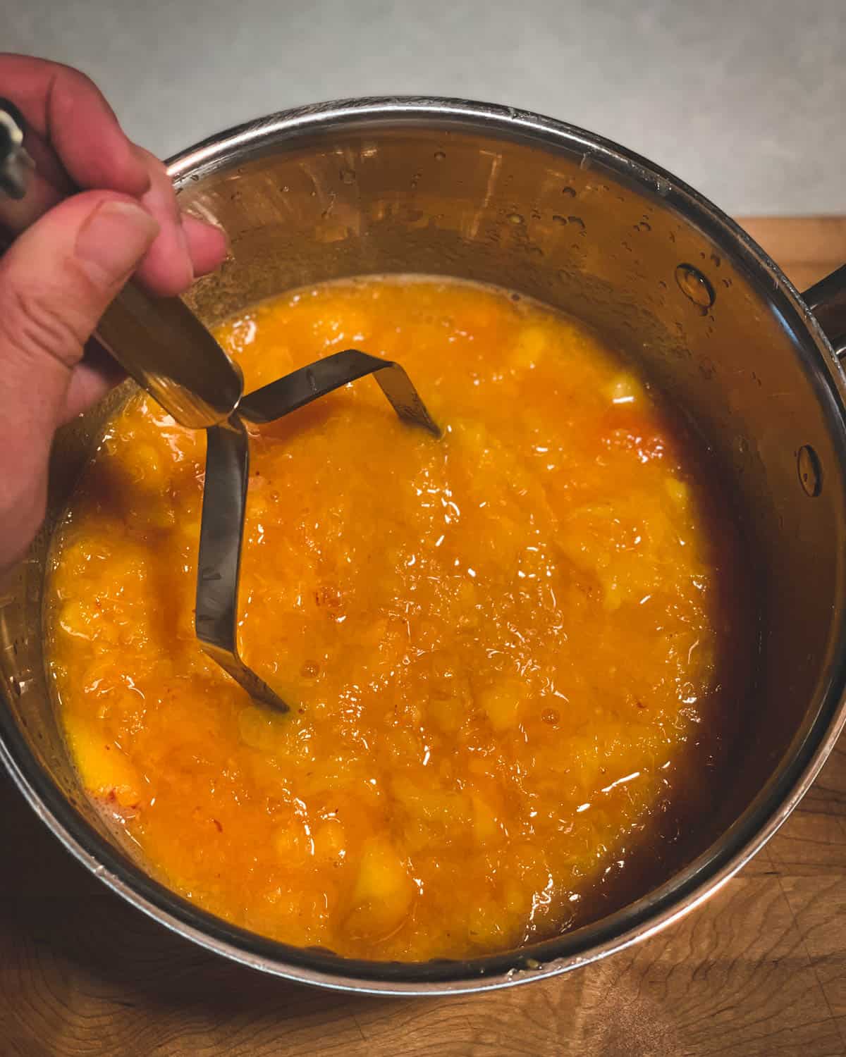 crushing the peaches with a potato masher