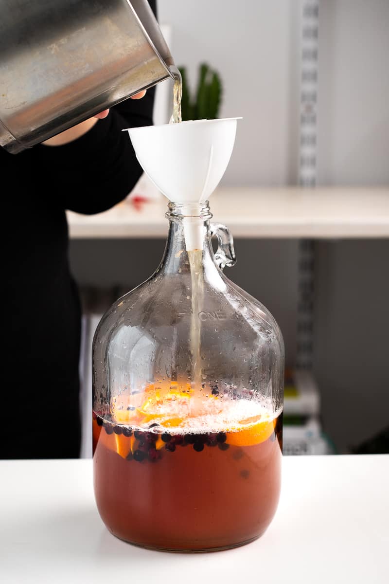 pouring the mead must into the jug with a funnel