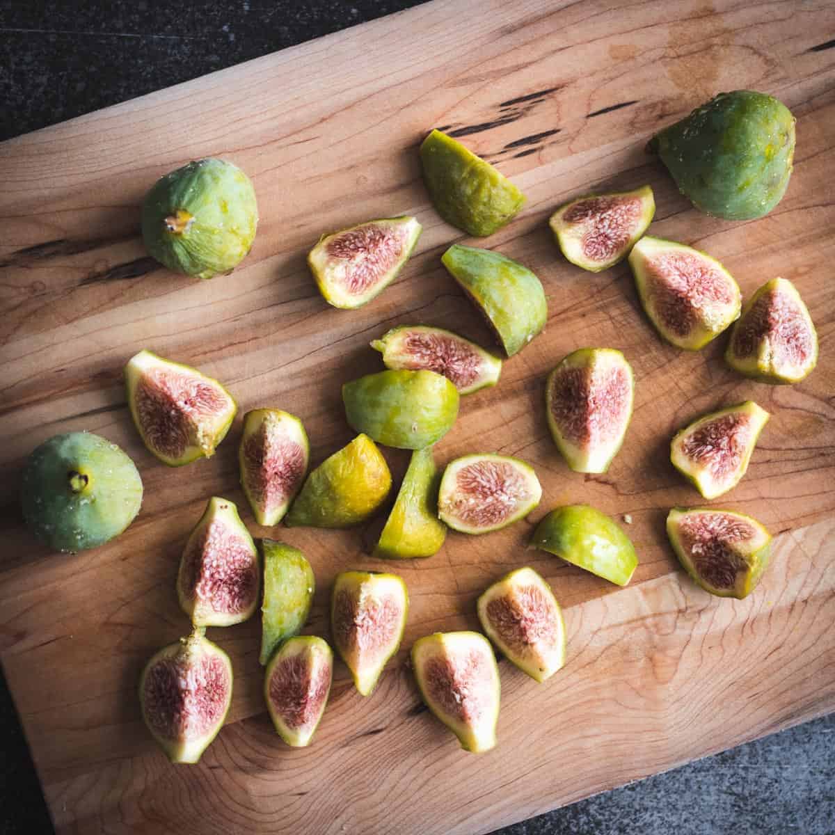 cut green figs on a cutting board