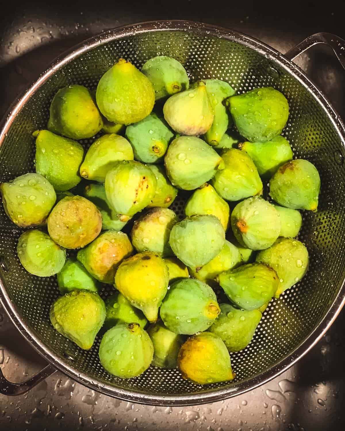 green figs being washed in a sink