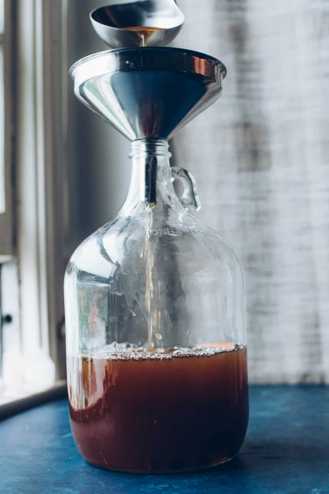 pouring warm apple juice into the jug with a funnel