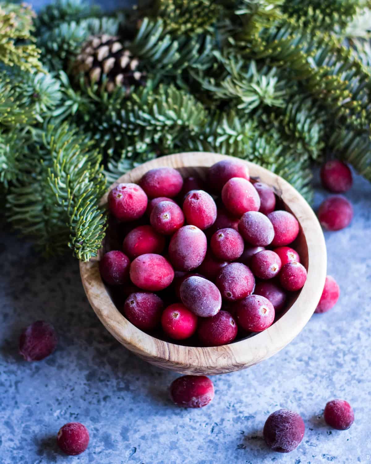 a wooden bowl of frosty whole cranberries