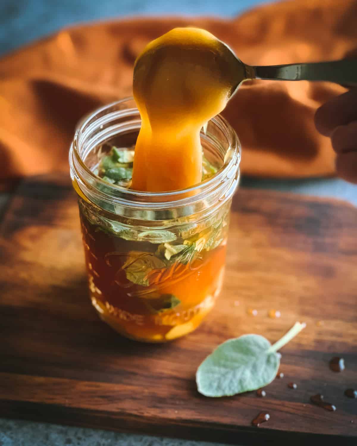 a spoon adding the honey to the oxymel