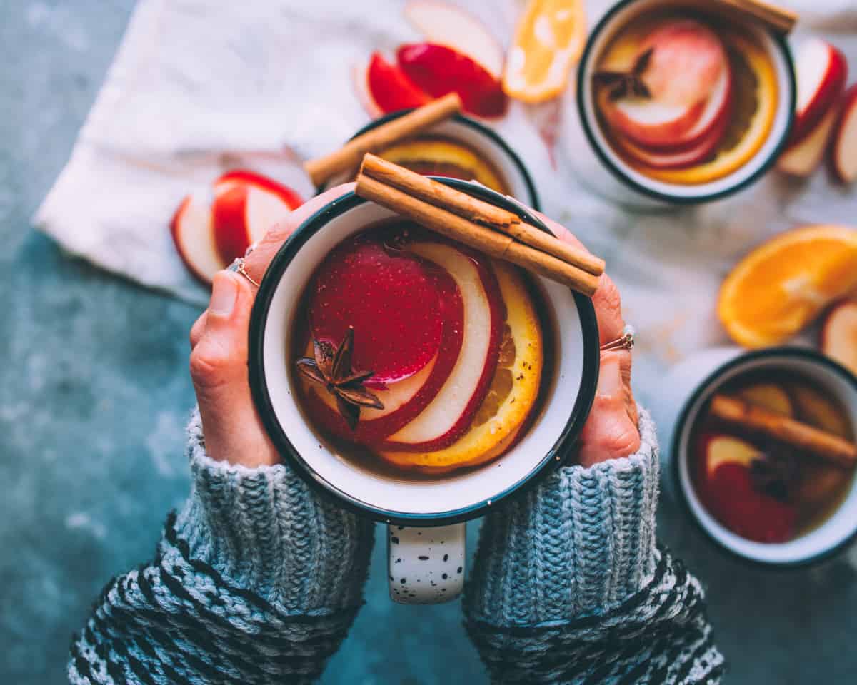 two hands holding a mug of mulled hard cider