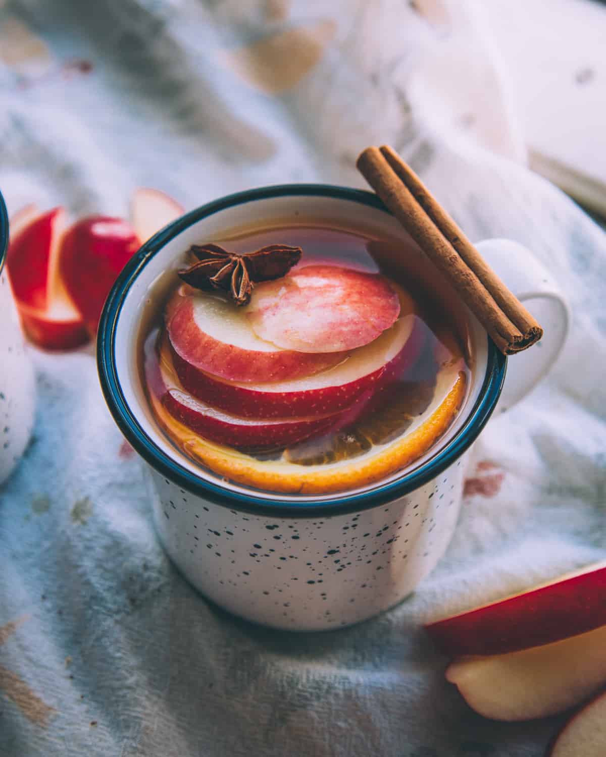 a mug of mulled hard cider with apples and a cinnamon stick for garnish