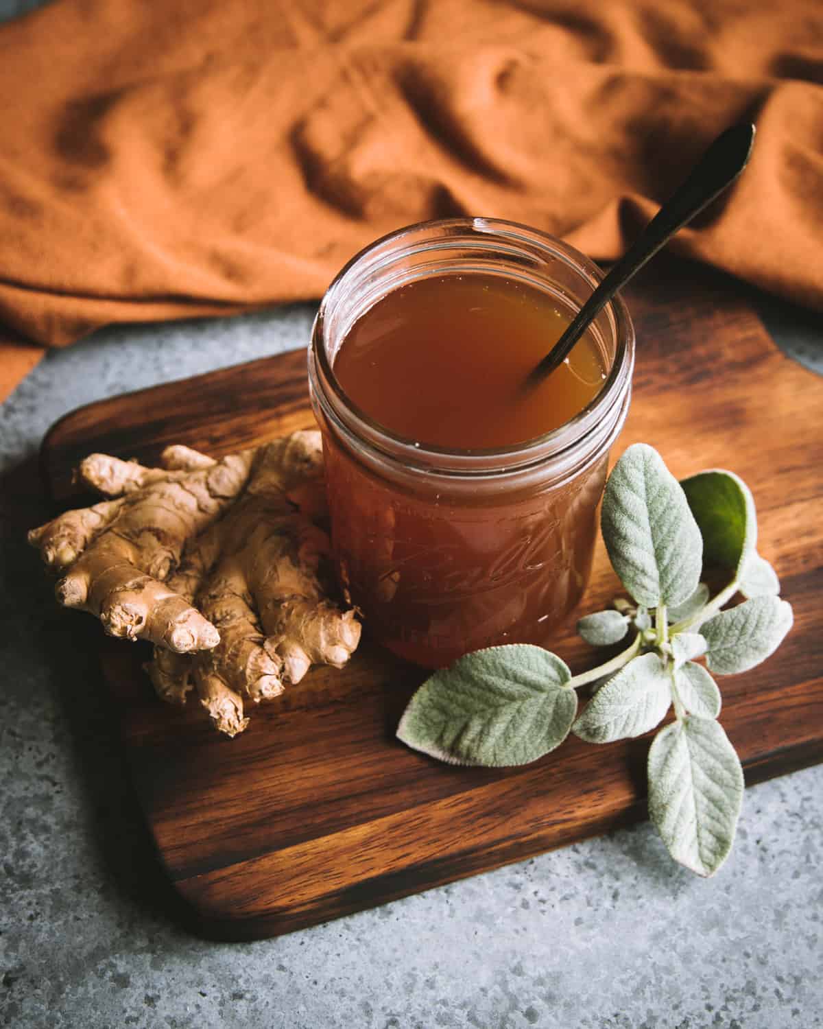 a jar of sage and ginger herbal oxymel with a spoon