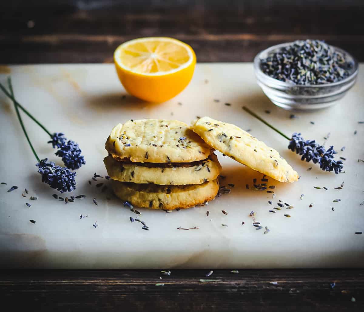 a stack of lemon lavender shortbread cookies on a board with lavender flowers
