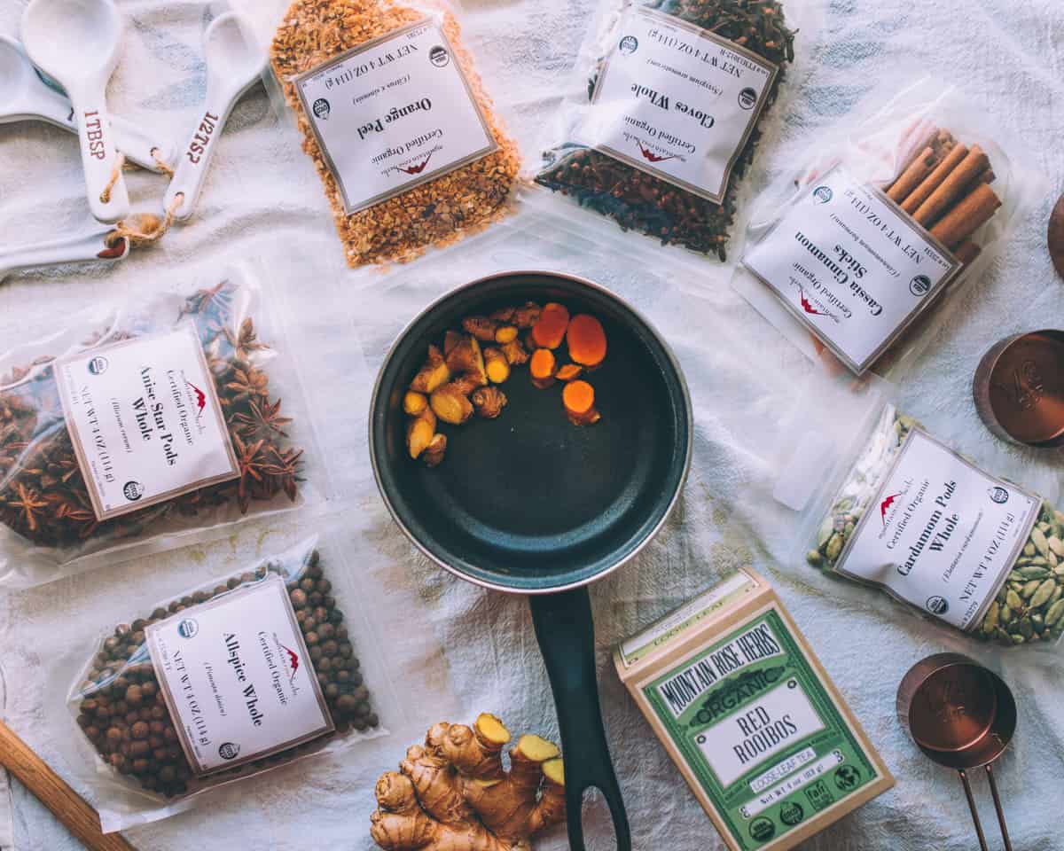 a pot with ginger and turmeric slices and bags of mountain rose herbs all around