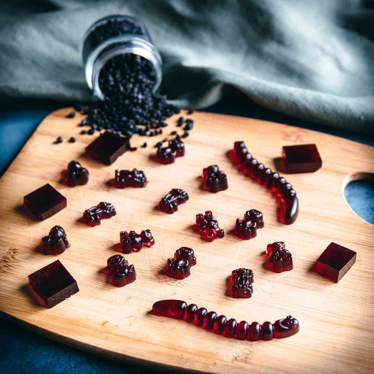 various elderberry gummies on a wooden board with dried elderberries