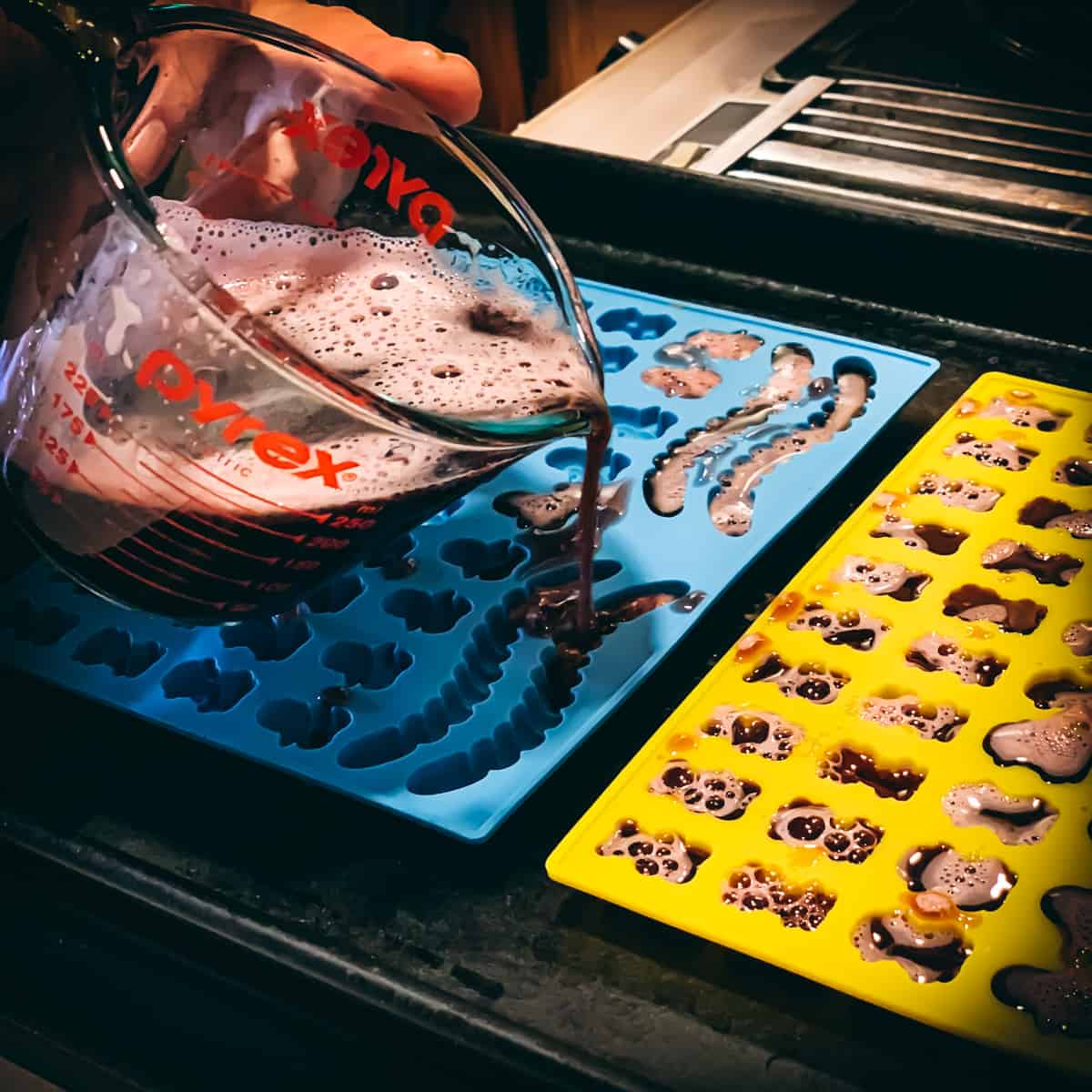 pouring the elderberry gummy mix into molds