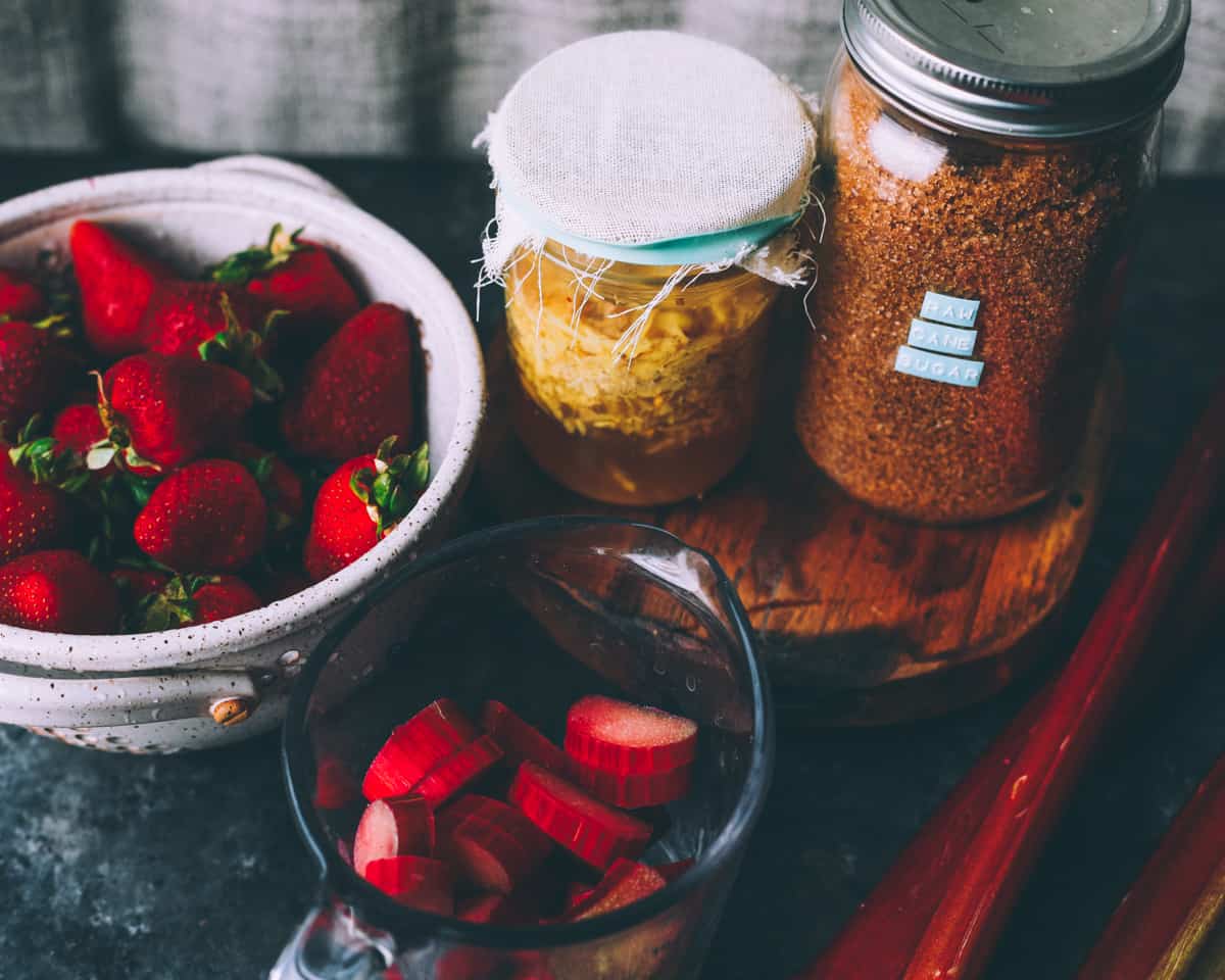 strawberries, rhubarb, ginger bug, and sugar on a table