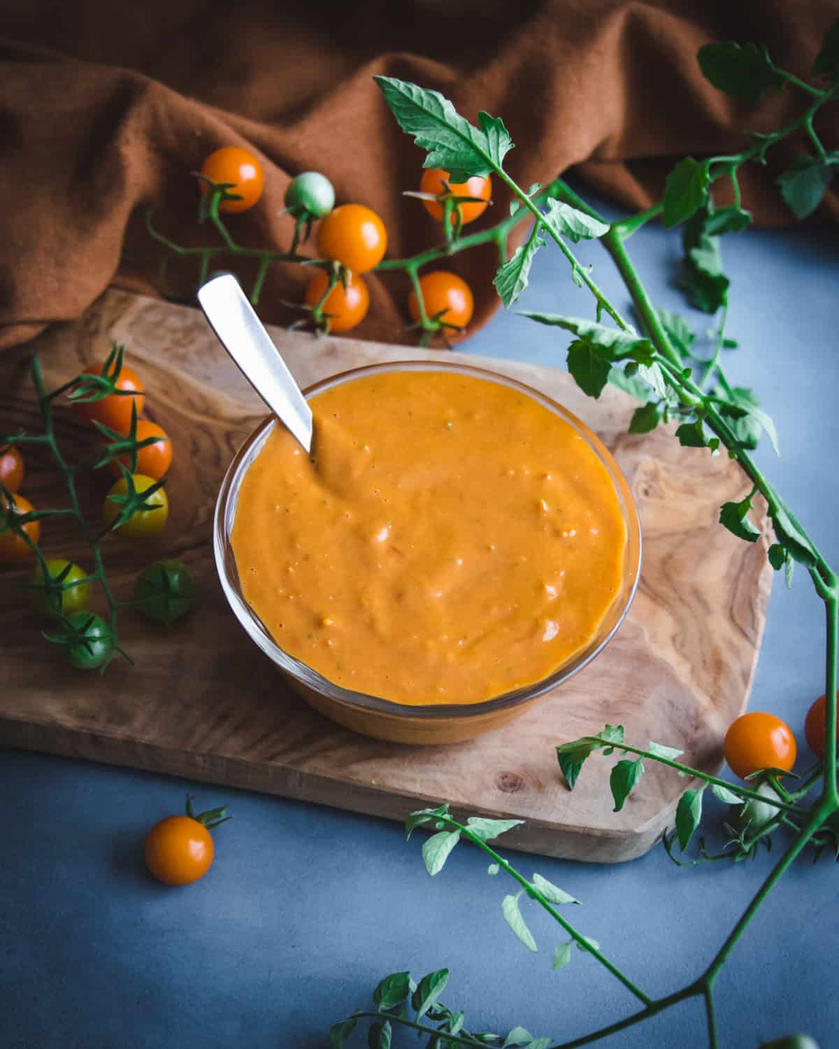 a bowl of roasted cherry tomato sauce on a wooden board with cherry tomatoes