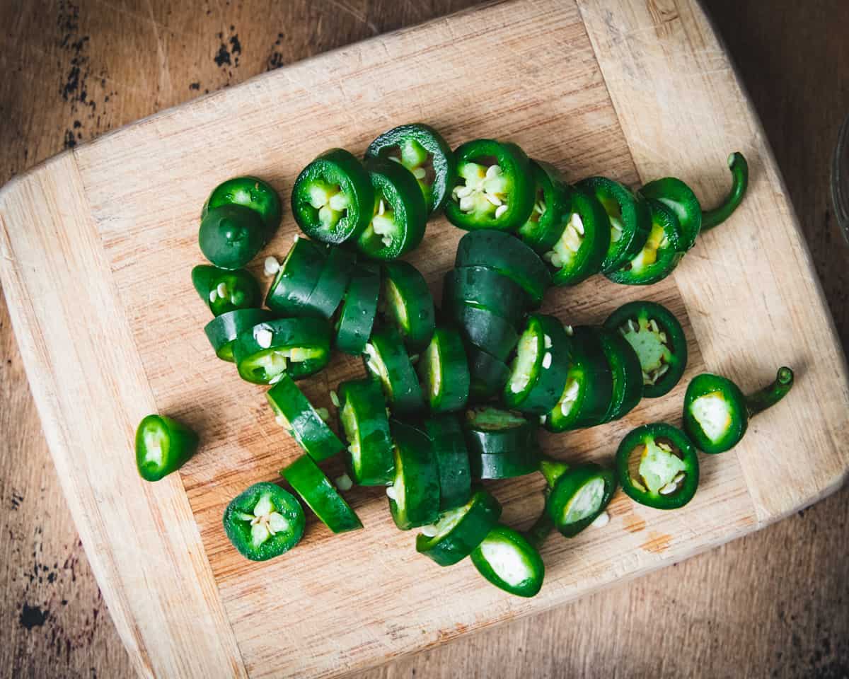 Fresh jalapeños sliced on a wood cutting board. 