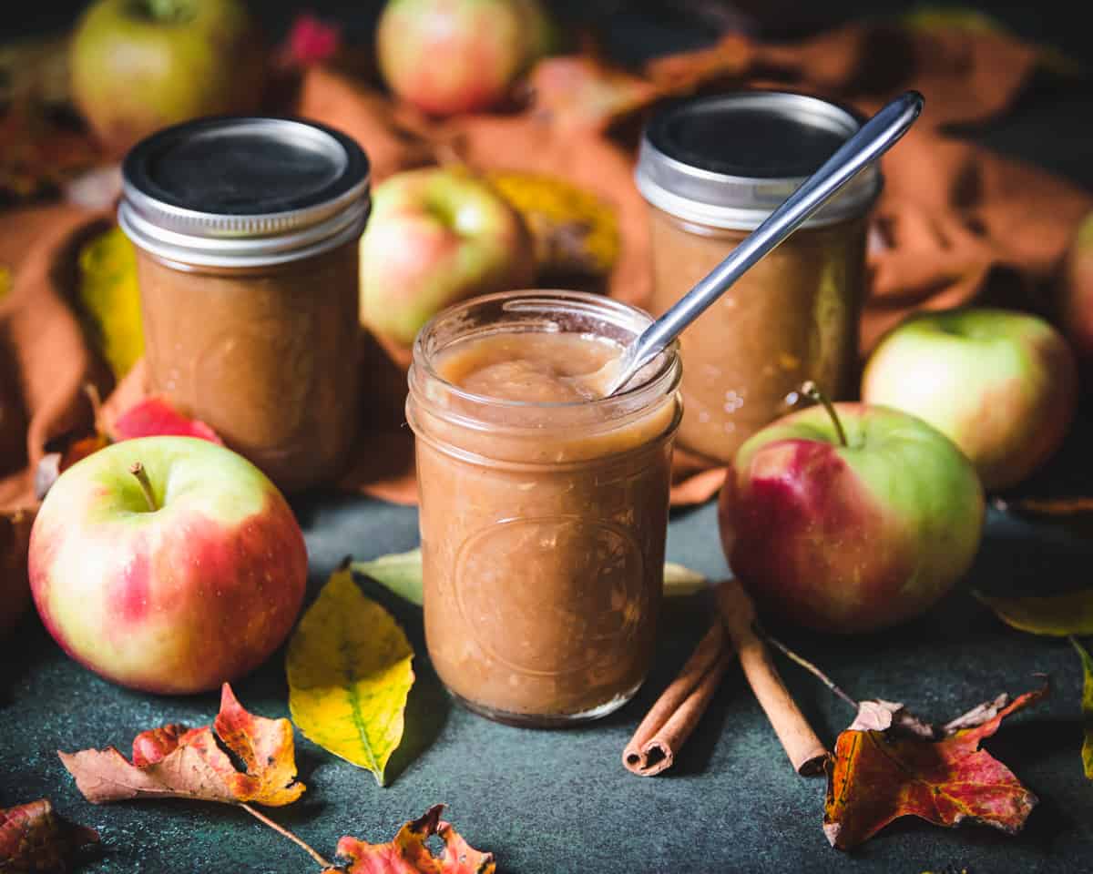 several jars of spiced apple butter, one open with a knife